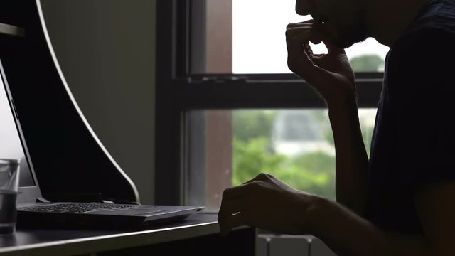 Biting nails man scrolling internet pictures laptop home, bad habit, self-doubt