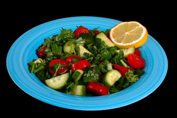 Tomatoes & cucumber fresh salad on a blue plate, on the black background. 