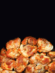 Pieces of roasted meat isolated on black background. Top view. Space for text
