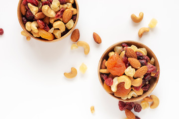 healthy snack: mixed nuts and dried fruits in wooden bowl on white background, almond, pineapple,...