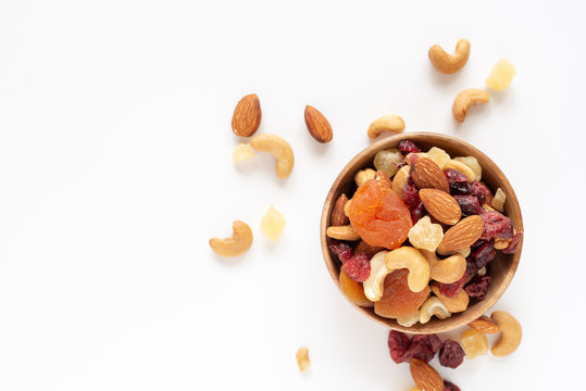 healthy snack: mixed nuts and dried fruits in wooden bowl on white background, almond, pineapple, cranberry, papaya, apple, strawberry, cherry, apricot, casshew.