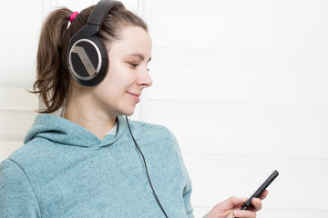 Young white brunette girl with player and in headphones listening to dance music on light house background.