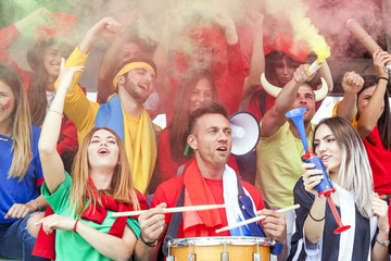 group of fans dressed in red color watching a sports event