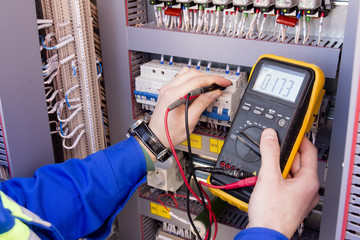 multimeter is in hands of engineer in electrical cabinet. Adjustment of automated control system...