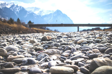 Steine im Fokus mit einer Brücke aus Holz und Bergen im Hintergrund