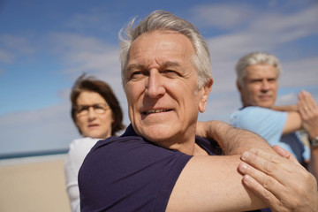 Portrait of senior people doing stretching exercises on the beach