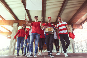 group of fans dressed in red color walking under the roof - obrazy, fototapety, plakaty