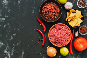 Ingredients for Mexican dishes chili con carne. Black concrete background, top view, space for text.