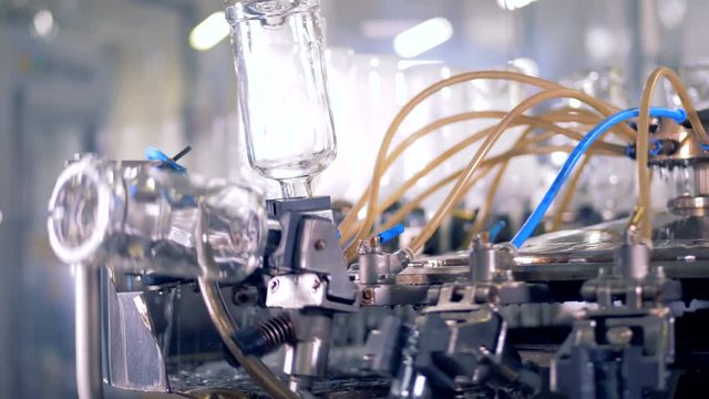 Glass bottles move up on a machine to be cleaned. 4K.