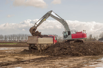 Excavator loads truck with soil