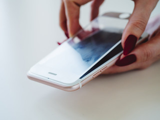 Smartphone with screen protect glass cover in hands. White background