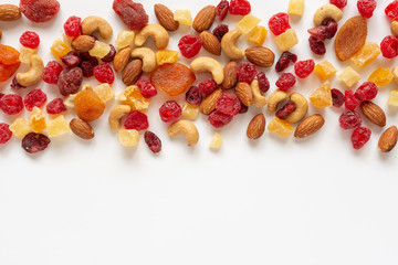 healthy snack: mixed nuts and dried fruits on white background from above, almond, pineapple, cranberry, papaya, apple, strawberry, cherry, apricot, casshew.