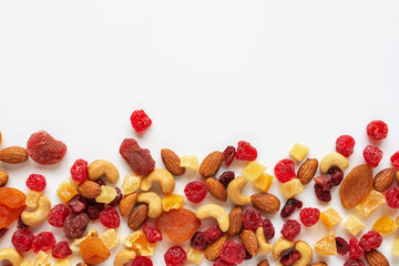 healthy snack: mixed nuts and dried fruits on white background from above, almond, pineapple,...