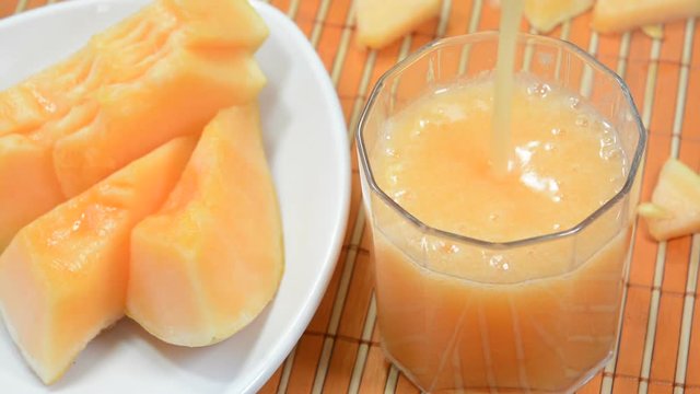 Pouring cantaloupe juice also known as muskmelon juice in a cup.