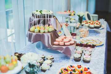 Delicious sweets on wedding candy buffet with desserts, cupcakes