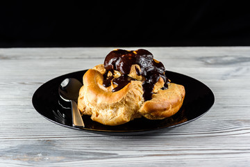 chocolate eclair on a black plate on a wooden background