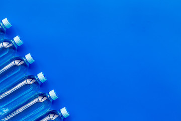 Drinking water in bottles on blue background top view copy space