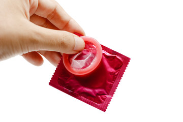 Hand holding male condom with package on white background