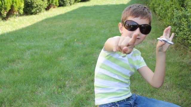 little boy playing with spiner on the grass