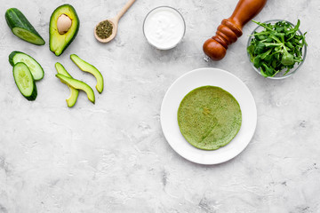 Healthy snacks spinach pancakes on grey background with spinach leaves, avocado, cucumber and spices top view copy space