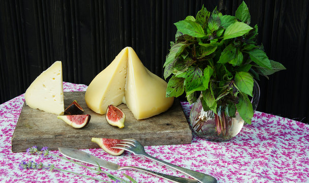 Tetilla cheese with with figs and basil on a wooden cutting board