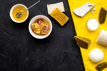 Honey spa set with natural honey, soap, cream, towel and pumice stone on black background top view...