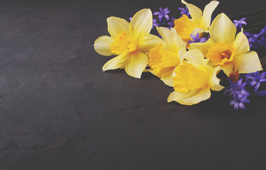 Obraz na płótnie Canvas bouquet of daffodils and lilac flowers on a black background, copy space
