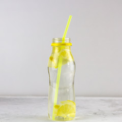 water with lemon in bottle with cocktail straw
