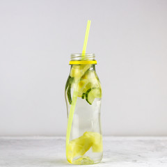 water with lemon and cucumber in bottle with cocktail straw