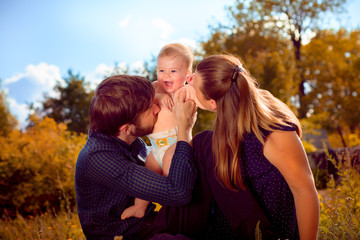 Fototapeta premium Mom and Dad kiss their son to laugh