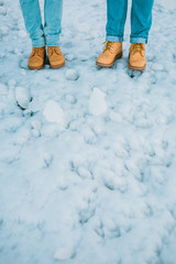 Couple in a brown hiking boots and blue jeans stand on ice. Iceland. Copy space