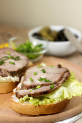 Appetizing sandwiches with meat, lettuce and sauce served with olives. Rustic style.