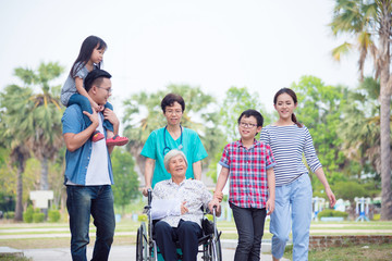 Obraz premium Senior female patient sitting on wheelchair with her family and nurse in park