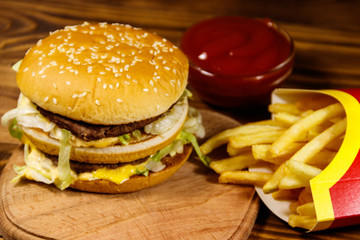 Delicious big hamburger with french fries and ketchup on wooden table