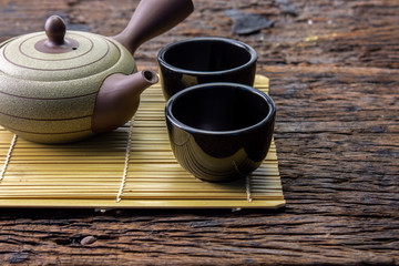 Hot tea pot on bamboo mat with cup on wooden table, chinese or japanese lifestyle