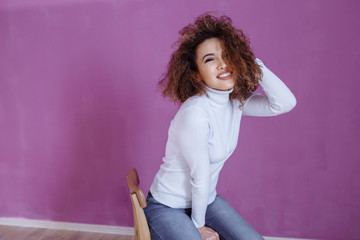 Obraz na płótnie Canvas curly girl in a turtleneck on a purple background.