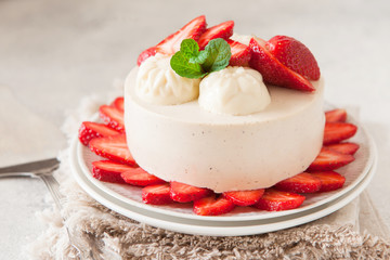 Light cheesecake with strawberry filling decorated with fresh berries and min, healthy organic summer dessert pie.
