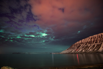 northern lights over the mountains and a cloudy sky