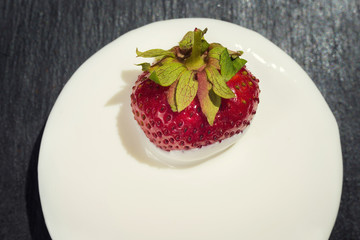 strawberries with cream on stone background, delicious first class organic fruit as a concept of summer vitamins