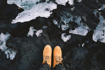 Traveler in hiking boots stand on black sand. Iceland. Top view - 200425668