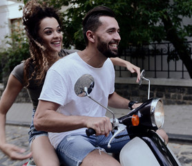 Obraz premium Stylish young couple sits a scooter in the street.