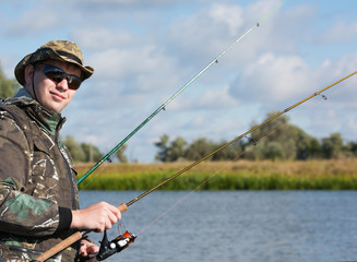 A fisherman with a spinning rod to catch fish. Sunglasses and fishing clothes