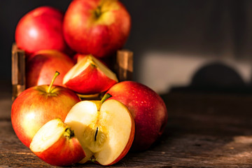Apples whole and cut in halves on wooden surface