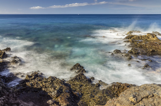 Long exposure photo of the ocean in Los Cristianos with breaking waves over the rocks
