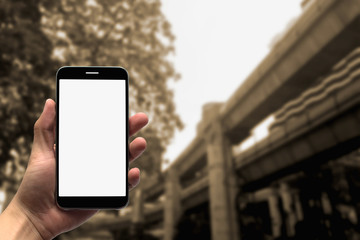 holding the mobile phone on a blurry background.