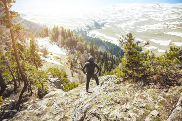 the guy the traveler stands on top of the mountain. .View from back of the tourist traveler on background mountain