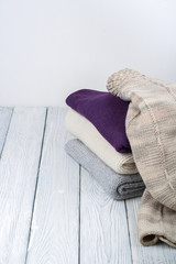 Knitted wool sweaters. Pile of knitted winter clothes on wooden background, sweaters, knitwear, space for text.