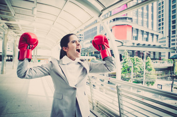 businesswoman wearing red boxing gloves throwing a punch