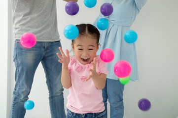Happy children playing with their parents, having fun with colorful balls.