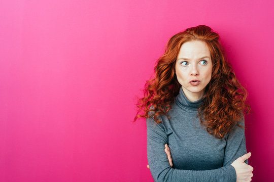 Young thoughtful woman against pink background